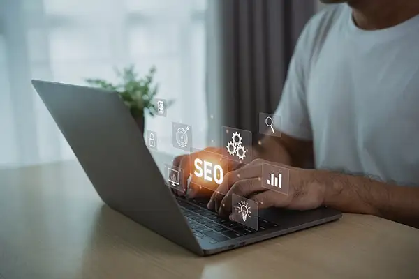 Hands typing on laptop with SEO icons Hands typing on laptop with SEO icons